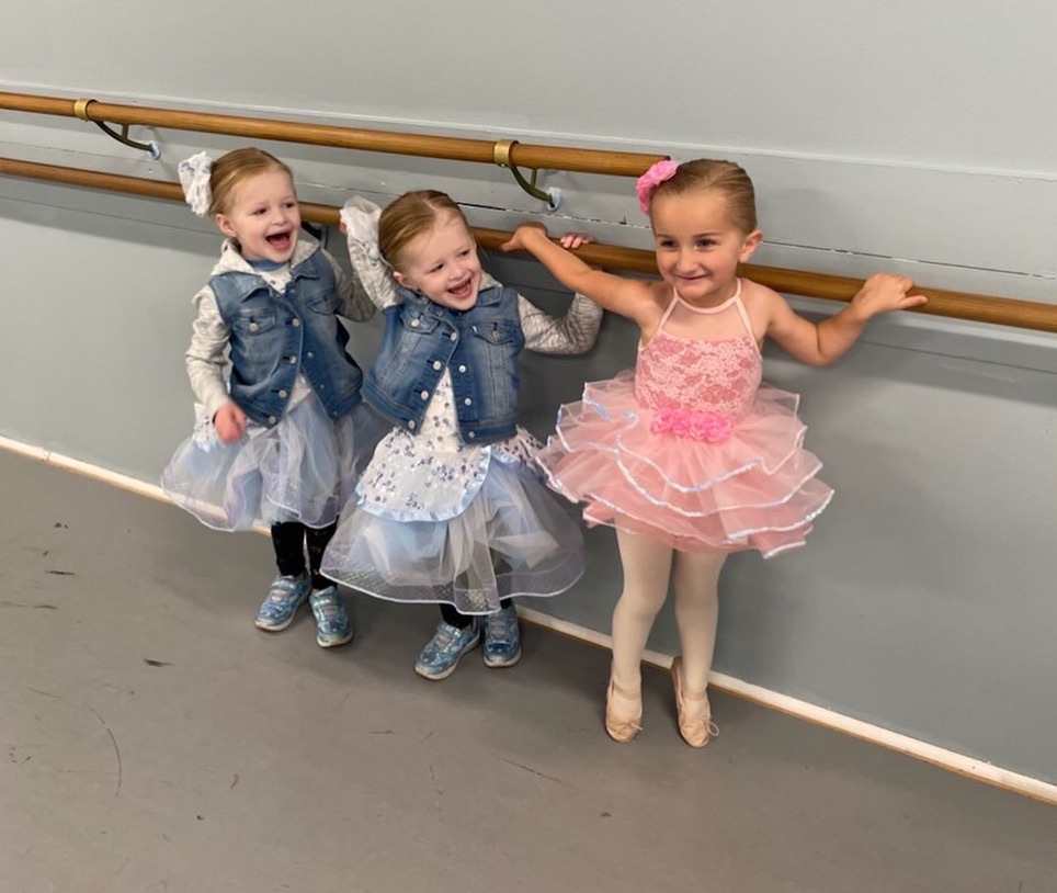 Young kids holding onto the ballet bar and smiling at BellePAC