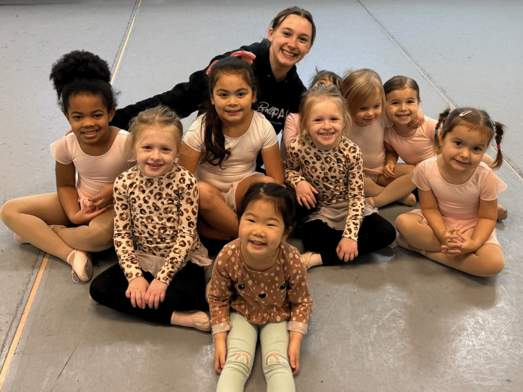 Ten dance students age 3 to 9 sitting and smiling on the floor during a dance class at BellePAC in Nashville, TN.